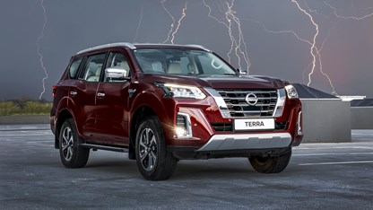 Red Nissan Terra in open field with lighting in background